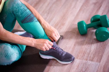 Spor haberleri. Spor salonundaki kadın egzersiz yapıyor ve yerde gülümsüyor.