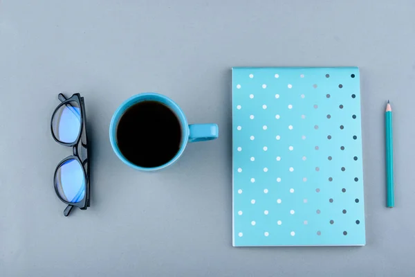 Blå anteckningsbok med en blå penna på en grå bakgrund. Telefon, glas och en kopp kaffe. — Stockfoto