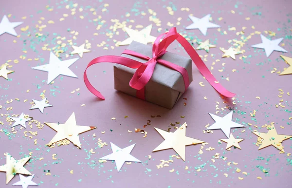 Un cadeau avec un vol rose sur un fond de fête avec des étoiles . — Photo