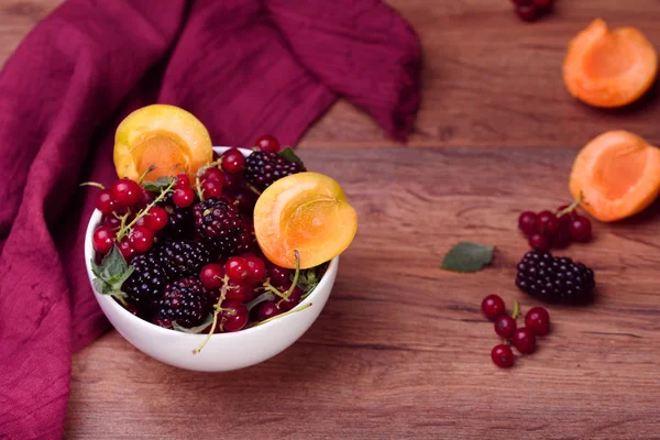 Reife und schmackhafte Beeren in weißer Schüssel auf dem Tisch — Stockfoto