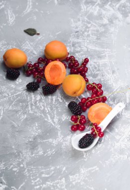 Farklı çilek patlaması. Fotoğraf, kırmızı frenk üzümü, siyah frenk üzümü, böğürtlen, kayısı somut bir arka planda.