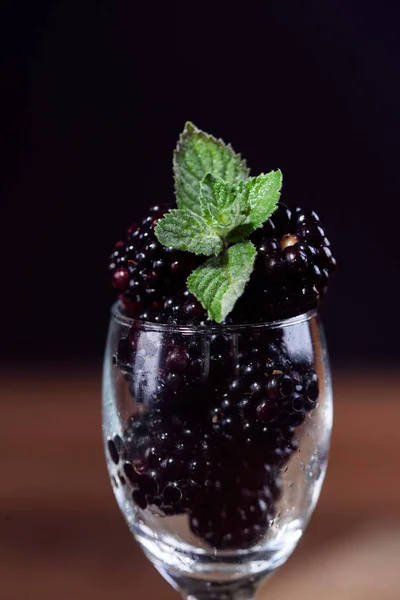 Reife und schmackhafte Brombeeren im Glaskelch mit Minzblatt — Stockfoto