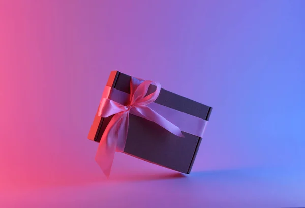 Geschenkbox mit rosa Schleife in Neonlicht — Stockfoto