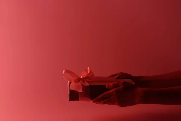 Gift box with a pink ribbon in neon light with a red tint — Stock Photo, Image