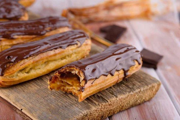 Sabrosas y hermosas eclairs con chocolate en una tabla de madera. Postres apetitosos. Artículos de fiesta — Foto de Stock