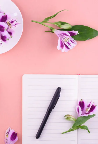 흰색 컵, 아름다운 꽃, 분홍색 배경, 펜과 안경이있는 노트북의 향기로운 차. — 스톡 사진