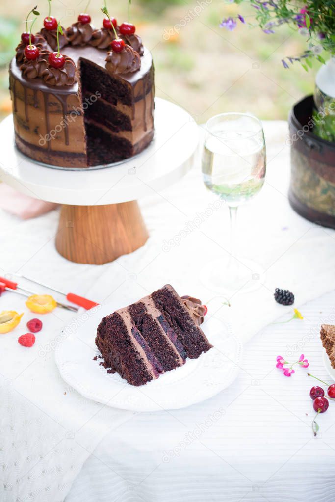 Delicious chocolate cake decorated with cherries with a glass of white wine