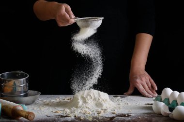 Şefin el çırpışı ve siyah arka planda beyaz un.