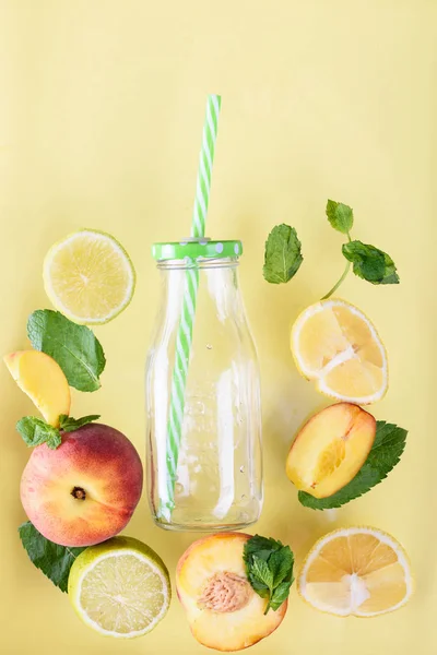 A cool drink with fresh fruit and ice. Peppermint, peach, lemon, lime. Yellow background