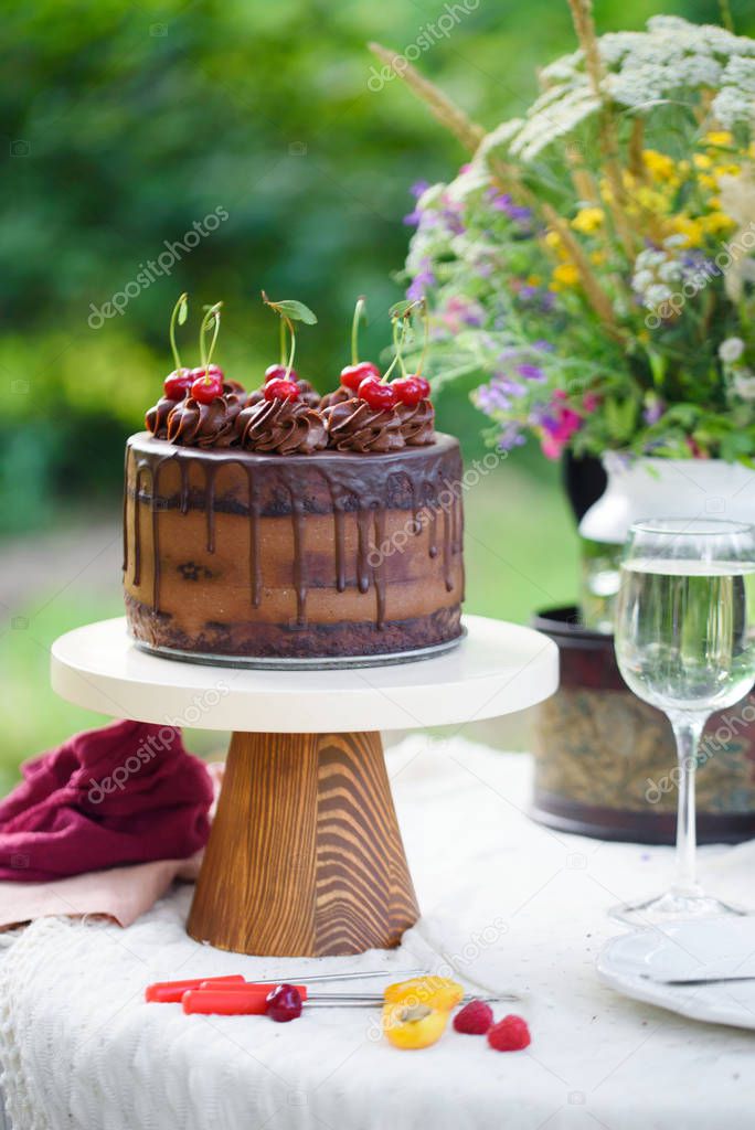 Delicious chocolate cake decorated with cherries with a glass of white wine