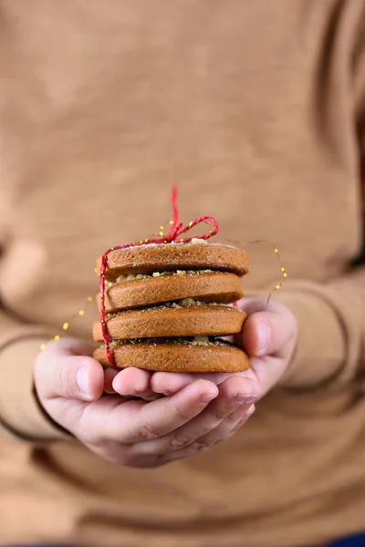Galletas de jengibre caseras, deliciosas y fragantes con cacahuetes, atadas con un hilo rojo en las manos de los niños — Foto de Stock