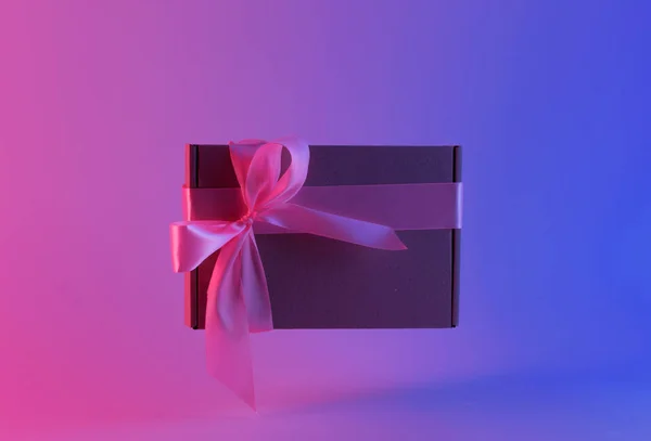 Geschenkbox mit rosa Schleife in Neonlicht — Stockfoto