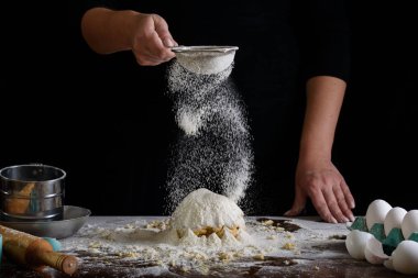 Şefin el çırpışı ve siyah arka planda beyaz un.