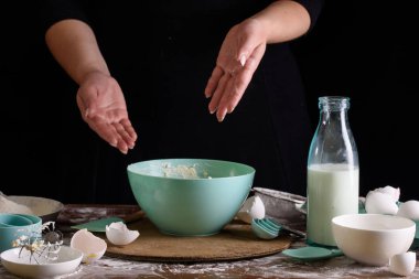 Şefin el çırpışı ve siyah arka planda beyaz un.