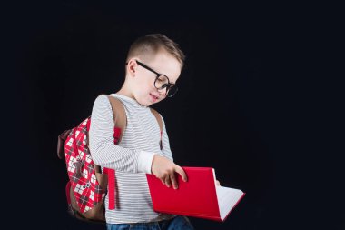 Siyah bir arka plan üzerinde neşeli gülümseyen küçük çocuk. Kameraya bakıyorum. Okul konsepti