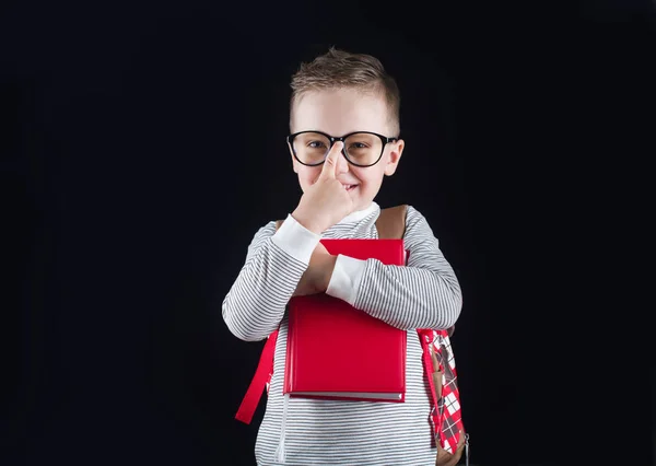 Fröhlich lächelnder kleiner Junge auf schwarzem Hintergrund. Blick in die Kamera. Schulkonzept — Stockfoto