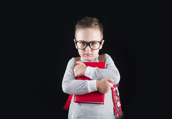 Fröhlich lächelnder kleiner Junge auf schwarzem Hintergrund. Blick in die Kamera. Schulkonzept — Stockfoto