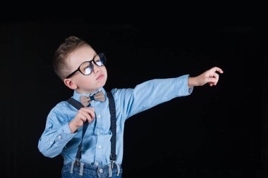 Siyah bir arka plan üzerinde neşeli gülümseyen küçük çocuk. Kameraya bakıyorum. Okul konsepti