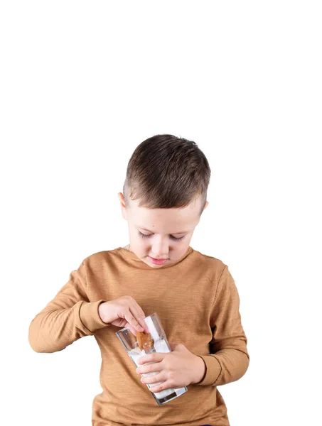 O menino segura em suas mãos um copo de leite e biscoitos caseiros . — Fotografia de Stock