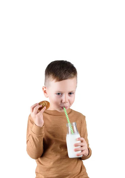 De jongen houdt in zijn handen een glas melk en zelfgemaakte koekjes. — Stockfoto