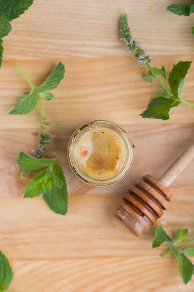 Smakelijke en aromatische honing in een potje met munt op een houten tafel. — Stockfoto