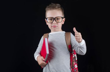 Siyah bir arka plan üzerinde neşeli gülümseyen küçük çocuk. Kameraya bakıyorum. Okul konsepti