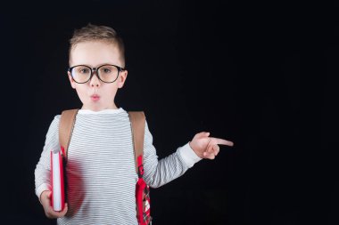 Siyah bir arka plan üzerinde neşeli gülümseyen küçük çocuk. Kameraya bakıyorum. Okul konsepti