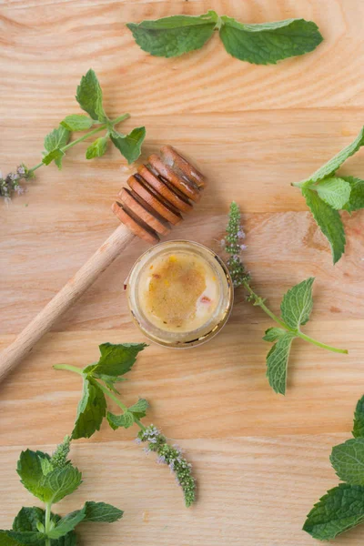 Smakelijke en aromatische honing in een potje met munt op een houten tafel. — Stockfoto