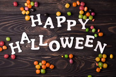 Cadılar Bayramı parti içeriği. Küçük renkli tatlılar ile beyaz halloween yazıt.