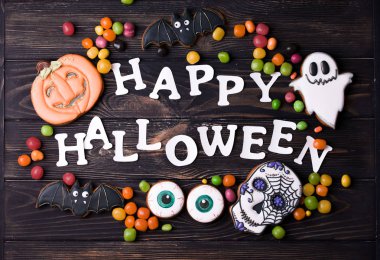 Cadılar Bayramı parti içeriği. Küçük renkli tatlılar ile beyaz halloween yazıt.