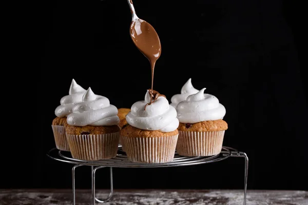 The process of making cupcakes, coating a cream from a pastry bag in the hands of a pastry chef.