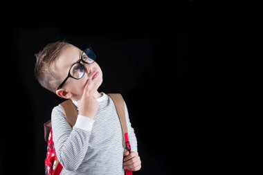 Siyah bir arka plan üzerinde neşeli gülümseyen küçük çocuk. Kameraya bakıyorum. Okul konsepti