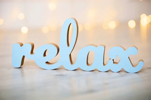 Wooden word relax on a bed with yellow blurred lights bokeh background — Stock Photo, Image