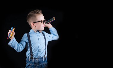 Siyah bir arka plan üzerinde neşeli gülümseyen küçük çocuk. Kameraya bakıyorum. Okul konsepti