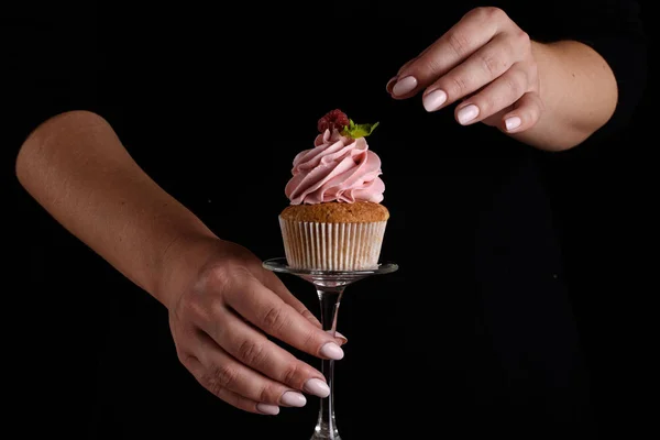 The process of making cupcakes, coating a cream from a pastry bag in the hands of a pastry chef.