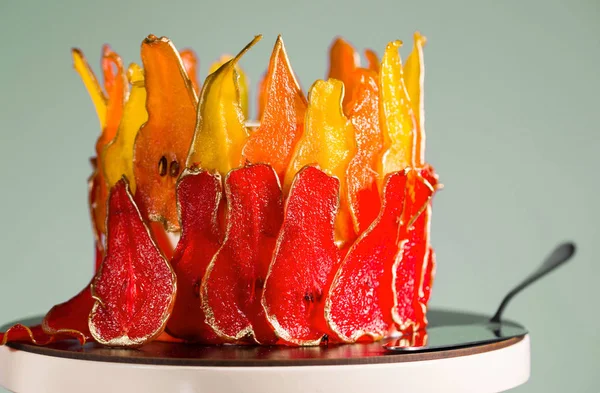 Beautiful and delicious dessert. The cake on the stand is decorated with red and yellow pears. — Stock Photo, Image