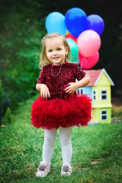 Niña en un hermoso parque con globos de gel y una casita . — Foto de Stock