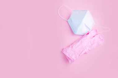 Pembe arka planda pembe eldivenli mavi yüz maskesi var. Virüsten korunma