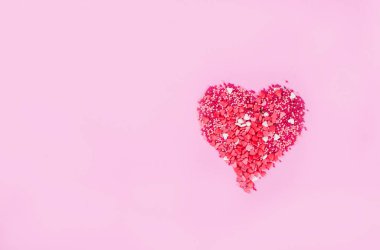 Pembe arka planda küçük tatlı kalplerden oluşan büyük bir kalp..