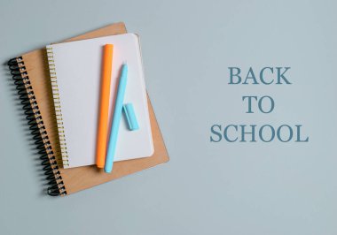 Okul konsepti, gri arka planda kalemleri olan defterler. Okula dön..