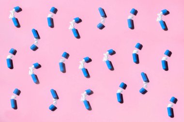 Mavi haplar, pembe arka planda bir hap şişesi. Desen