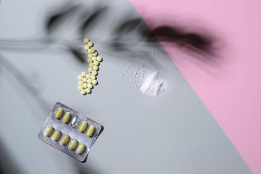 Farklı ilaçlar renkli arka planda, yaprakların gölgesinde yatar. Metin için yer, üst görünüm