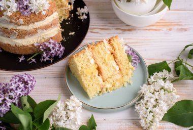 Kremalı bisküvi, hindistan cevizi ve ananasla hamile bırakılmış, leylak çiçekleriyle süslenmiş. Lezzetli tatlı, yemek fotoğrafı..