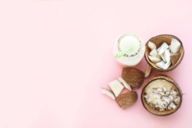 Parça parça hindistan cevizi, pembe arka planda hindistan cevizi talaşı. Yukarıdan bak. Mesaj için yer. Düz yatıyordu