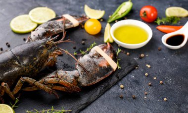 Karanlık arka planda nefis taze ıstakoz. Kokulu bitkilerle, baharatlarla ve sebzelerle dolu deniz ürünleri.