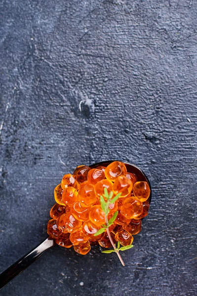 スプーンと黒の背景に氷とガラス板にサーモンキャビア 魚介類 — ストック写真