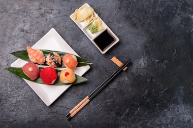 Pirinçten yapılmış suşi ruloları, füme yılan balığı, krem peynir ve uçan balık köftesi avacado, somon, krem peynir, yosun, soya sosu, karanlık bir masada zencefil. Suşi