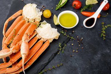 Taze yengeç pençeleri, kireç, baharatlar, baharatlar, buz, karides, arka planda sebzeler. Lezzetli deniz ürünleri sağlıklı yiyecekler