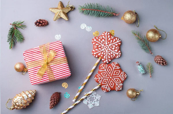 Beautiful packaged gift with gold ribbon, sequins, toys, bumps, sprigs of Christmas trees, gingerbread in the form of snowflakes. Holiday content. Flat lay