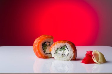 Kırmızı balık somonlu iki taze ve sulu suşi krem peynir, zencefil, salatalık, avacado, beyaz arka planda yansıması olan. Sushi, kapat.